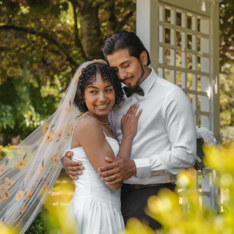 Bride and groom embracing in a garden during their wedding.