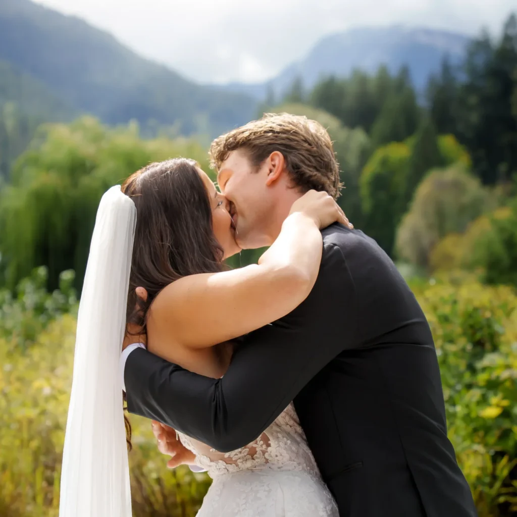 Bride and groom kissing with a mountain landscape in the background